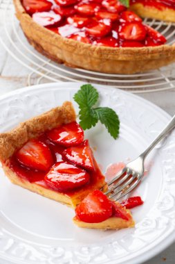Çilek yaprakları ve bir tabak içinde bölümü ile dekore edilmiş ev yapımı çilekli tart