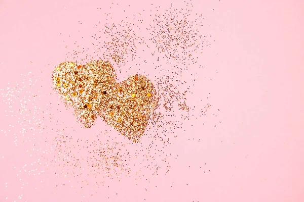Два золотых блестящих сердца на розовом фоне — стоковое фото