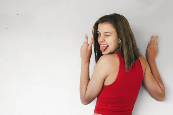 Дівчина-підліток робить знак перемоги підморгнув і витягнув язик — стокове фото