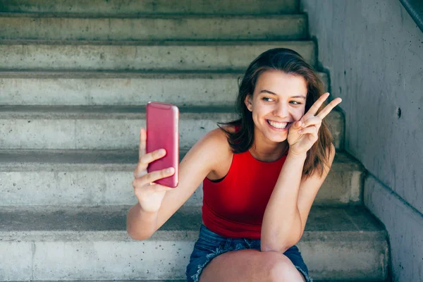 Divertido adolescente chica tomando un selfie sentado en las escaleras — Foto de Stock