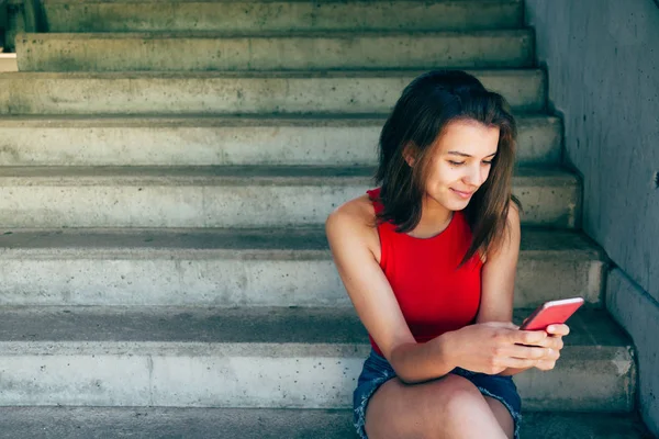 Šťastná teen dívka pomocí svého chytrého telefonu sedí na schodech — Stock fotografie