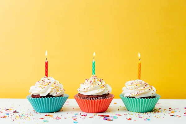 Tres Cupcakes Cumpleaños Coloridos Con Velas Confeti Sobre Fondo Amarillo —  Fotos de Stock