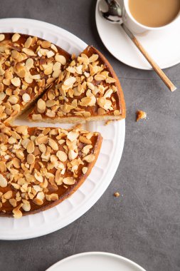 Badem ve limonlu pasta, üstüne dilimlenmiş badem ve beton bir yüzey üzerine bir kahve fincanı. Üst görünüm