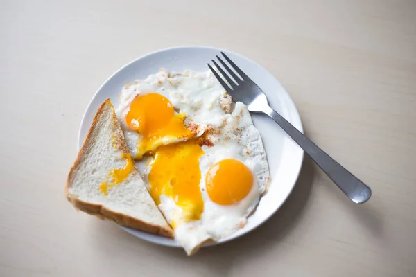 Twee gebakken eieren met sinaasappeldooiers, 's morgens geroosterd brood als ontbijt. — Stockfoto