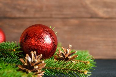 Kırmızı Noel oyuncağı, ladin dalları ve kozalaklar yeni yıl havası yaratır. Mutlu Noeller ve mutlu yıllar konsepti.