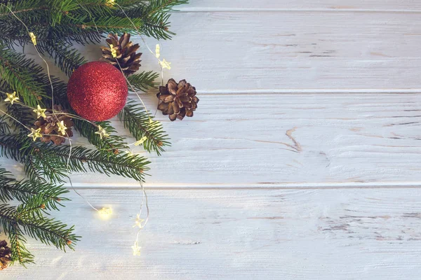 Kırmızı Noel oyuncağı, ladin dalları ve kozalaklar yeni yıl havası yaratır. Mutlu Noeller ve mutlu yıllar konsepti. Bulanık.