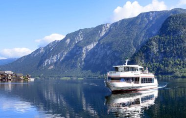 Hallstatt, Avusturya, Eylül 2019. Avusturya Alpleri 'nin ünlü dağ köyü sıcak bir sonbahar gününde. Göldeki eğlence teknesi. Yansıma. Avusturya 'nın pitoresk yerlerine seyahat etmek.