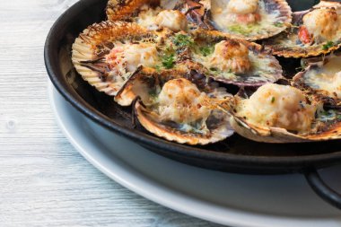 Peynirli ve baharatlı soslu fırında istiridye. Narin midye gerçek bir zevktir. İspanyol balık restoranında romantik bir akşam yemeği. Mallorca Adası, İspanya.