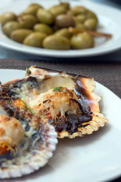 Vieiras al horno con queso y salsa picante. Una almeja delicada es un verdadero placer. Cena romántica en un restaurante español de pescado. Isla de Mallorca, España . —  Fotos de Stock