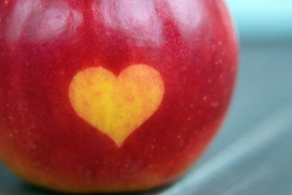 red apples with a heart seal on the table. Orange heart on organically grown fruits. Growing fruits with prints. Close-up