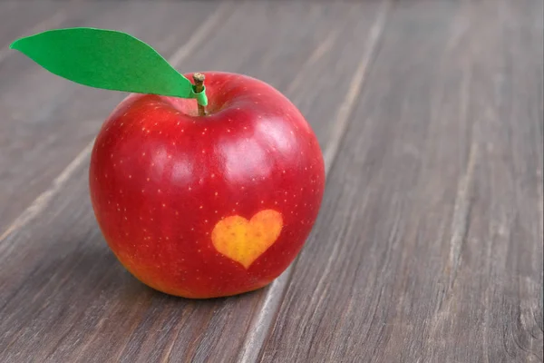 red apples with a heart seal on the table. Orange heart on organically grown fruits. Growing fruits with prints. Close-up