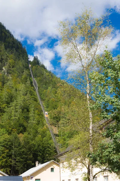 Hallstatt, Oostenrijk. Beroemd bergdorpje in de Oostenrijkse Alpen op een warme herfstdag. Uitzicht op de bergen, het bos en de kabelbaan. — Stockfoto