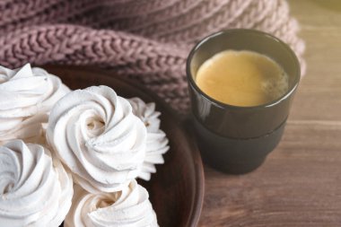 Kahverengi tabakta ev yapımı elma beyazı marşmelov ve ahşap bir masada siyah bir fincanda kahve. Tatlı zephyr ve aromatik kahve..