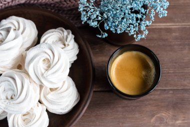 Kahverengi tabakta ev yapımı elma beyazı marşmelov ve ahşap bir masada siyah bir fincanda kahve. Tatlı zephyr ve aromatik kahve..