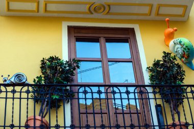 Sarı bir duvarın arka planında balkonda komik bir salyangoz. İspanya 'nın Valencia şehrindeki İspanyol balkonunda ilginç bir figür. Balkon giydirme.