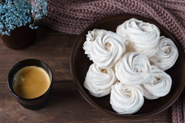 Kahverengi tabakta ev yapımı elma beyazı marşmelov ve ahşap bir masada siyah bir fincanda kahve. Tatlı zephyr ve aromatik kahve..