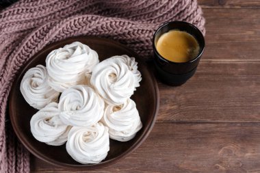Kahverengi tabakta ev yapımı elma beyazı marşmelov ve ahşap bir masada siyah bir fincanda kahve. Tatlı zephyr ve aromatik kahve..