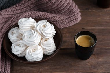 Kahverengi tabakta ev yapımı elma beyazı marşmelov ve ahşap bir masada siyah bir fincanda kahve. Tatlı zephyr ve aromatik kahve..
