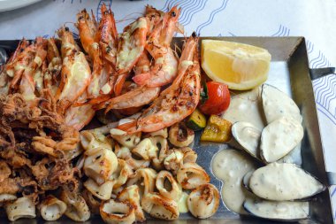 Kızarmış deniz ürünleri tabağı. Karides, kalamar, baharatlı soslu balık ve sebze. Kıbrıs adasındaki eski bir balık restoranında öğle yemeği. Gastronomik yolculuk.