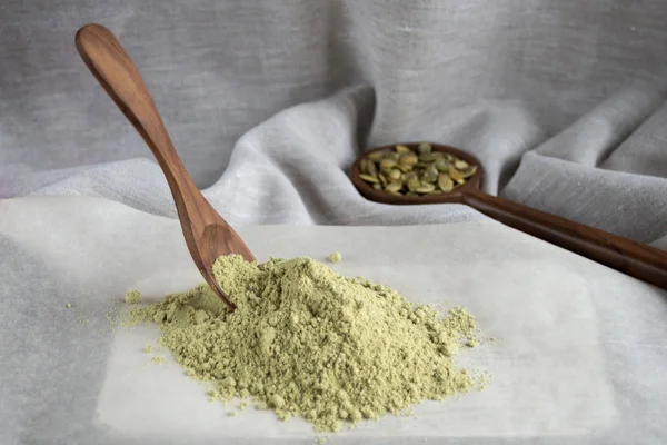 Beyaz arka planda balkabağı tohumları olan un arasında tahta kaşık. Alternatif un. Pişirmek için pişirme.