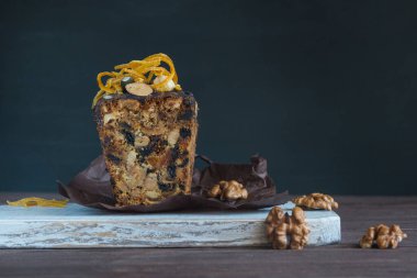 Kurutulmuş meyveli ve fındıklı lezzetli pasta, çikolata kremalı ve koyu arkaplanda portakallı şekerli meyve. Geleneksel Alman Noel pastası Stollen.