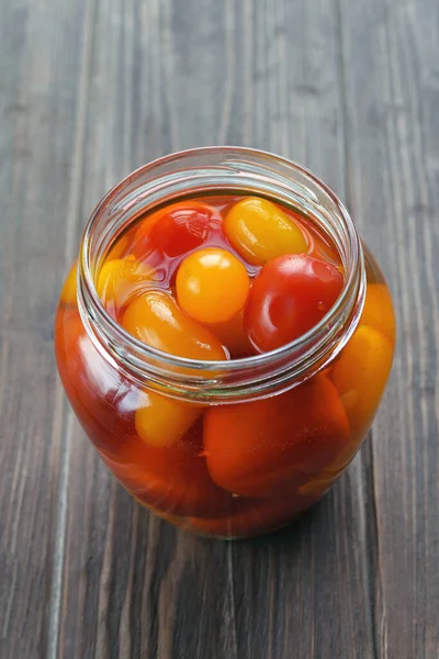 Fermented foods. Salted tomatoes in a glass jar on a dark wood background. Vegetarian food. Super food.