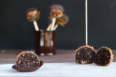 Koyu arkaplanda hindistancevizi taneleri olan çikolatalı pasta. Tahta çubukta mini kekler. Popüler bir tatlı..