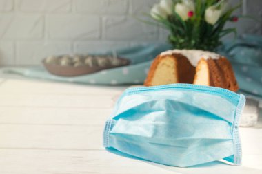 Paskalya fırınının arka planında tıbbi mavi tek kullanımlık maske. Virüslere karşı koruma. Koronavirüs salgını bağlamında Kutsal Paskalya kutlamaları..