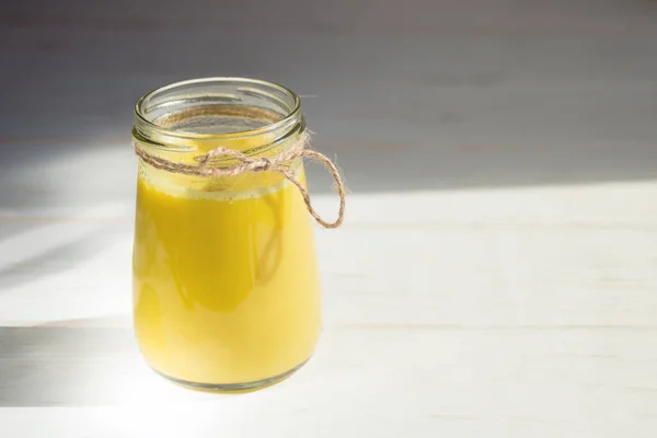玻璃瓶 由姜黄 牛奶和胡椒制成 白色木制底座上有健康的金牛奶饮料 预防疾病和病毒 — 图库照片