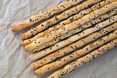 Geleneksel İtalyan ekmek kırıntısı ince gevrek Grissini çubukları ve el işi kağıdında siyah susam tohumu ve peynir. İtalya 'nın ulusal mutfağı.