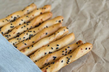 Geleneksel İtalyan ince çıtır Grissini çubukları ve siyah susam tohumları ve peynir keten peçetesi. İtalya 'nın ulusal mutfağı.