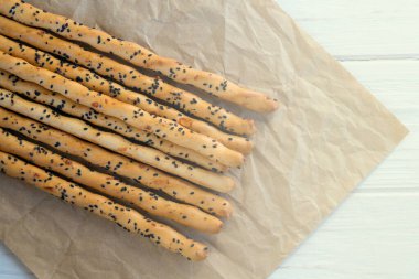 Geleneksel İtalyan ekmek kırıntısı ince gevrek Grissini çubukları ve el işi kağıdında siyah susam tohumu ve peynir. İtalya 'nın ulusal mutfağı.