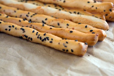 Geleneksel İtalyan ekmek kırıntısı ince gevrek Grissini çubukları ve el işi kağıdında siyah susam tohumu ve peynir. İtalya 'nın ulusal mutfağı.