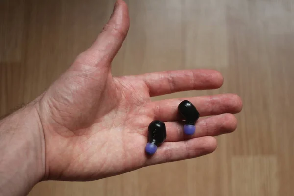 Black bluetooth earphones on a palm