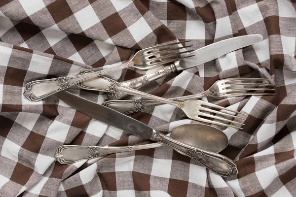 Silverware on a white and brown checked fabric — Stock Photo, Image