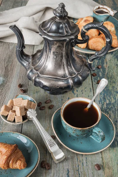 Cup of coffee, coffee pot and croissants — Stock Photo, Image