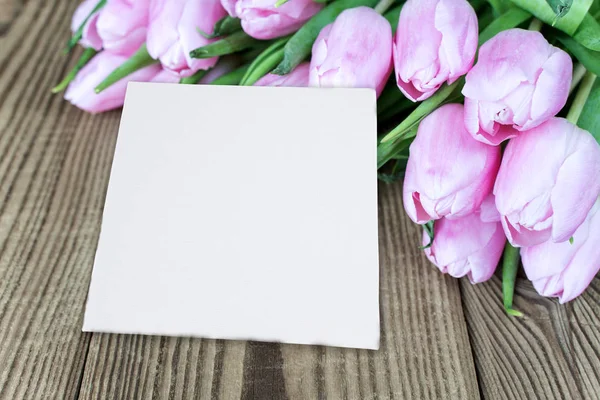 Цветы тюльпана и открытка на деревянном фоне — стоковое фото