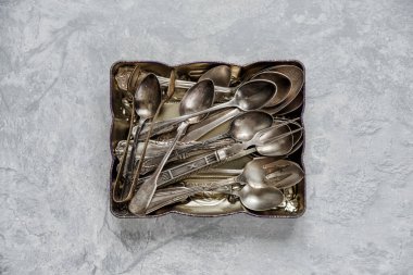 Gri taş masanın arka planında metal bir tepside çeşitli gümüş çatal bıçaklar.