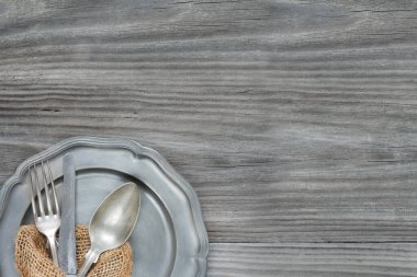 Antika kaşık, bıçak ve çatal eski gri ahşap arka planda kalay plaka üzerinde, kopyalama alanı ile