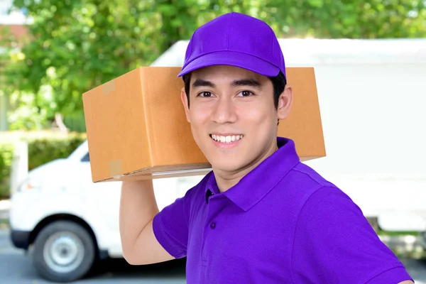 Sorrindo amigável entrega homem transportando caixa de pacote — Fotografia de Stock