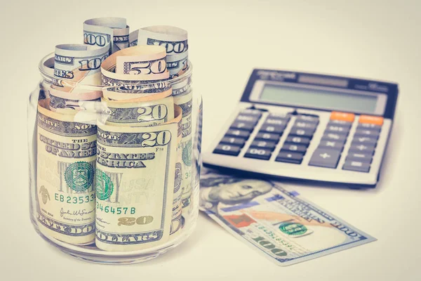 Dinero, billetes en dólares estadounidenses, con calculadora sobre mesa blanca —  Fotos de Stock