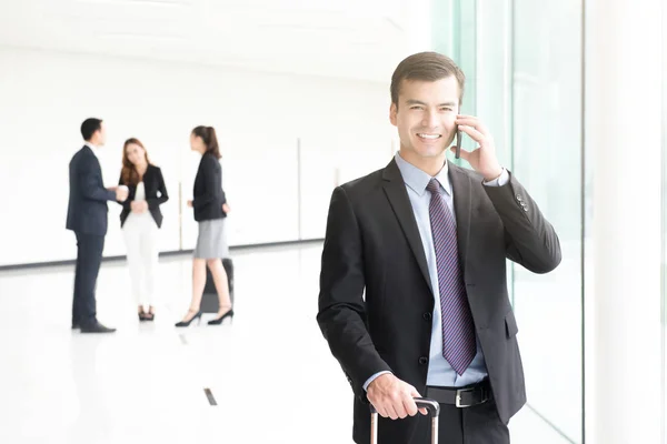 Viajando hombre de negocios llamando en el teléfono inteligente en el pasillo del edificio —  Fotos de Stock