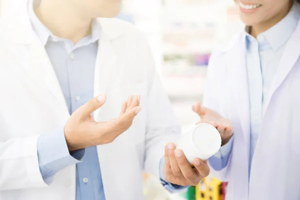 Apotheker holding geneeskunde fles en bespreken in apotheek — Stockfoto