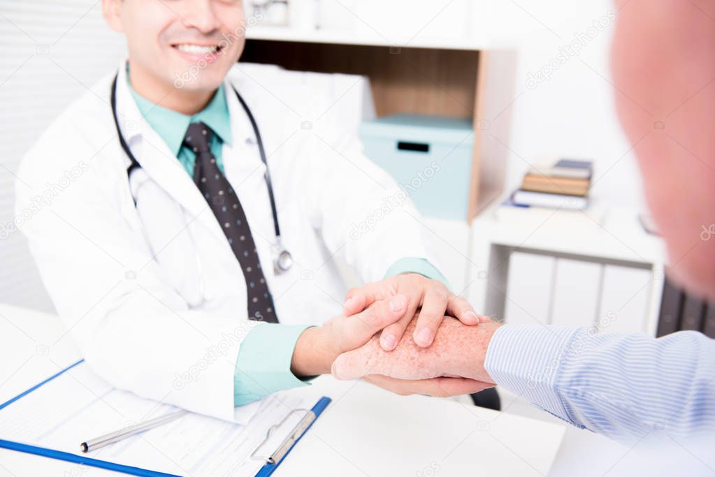 Doctor holding senior male patient hand 