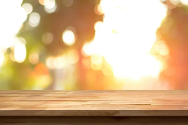 Houten tafelblad op vervagen bokeh achtergrond van zonlicht schijnt door de bomen — Stockfoto