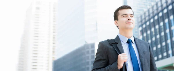 Businessman carrying bag and looking forward on blur office building background — Stock Photo, Image