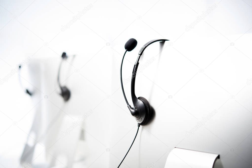 Microphone headsets hanging on computer monitors 