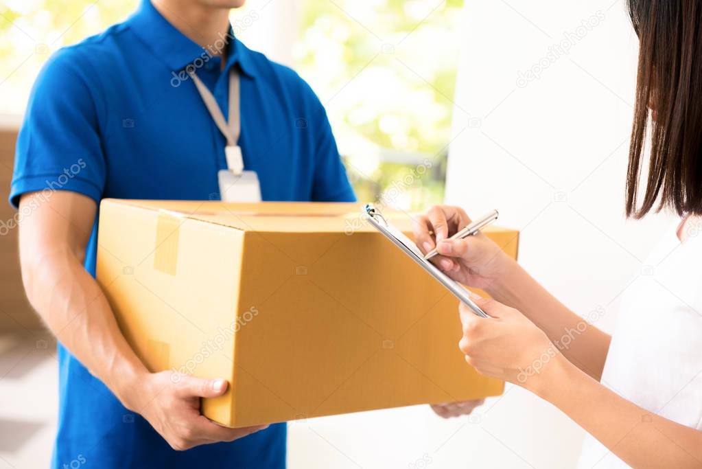 Woman receiving parcel from a delivery man