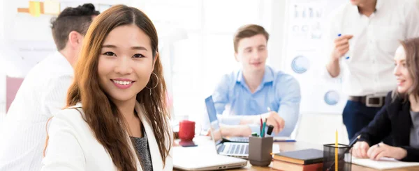 S úsměvem mladá jistý asijské podnikatelka v kanceláři s její kolegové Smíšené rasy — Stock fotografie