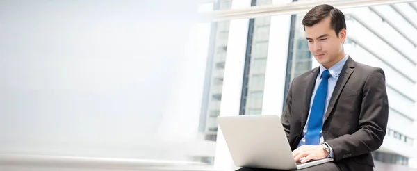 Businessman using laptop computer while sitting outdoor — Stock Photo, Image